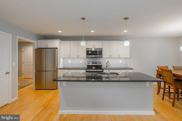 kitchen featuring sink, an island with sink, white cabinets, light hardwood / wood-style flooring, and appliances with stainless steel finishes