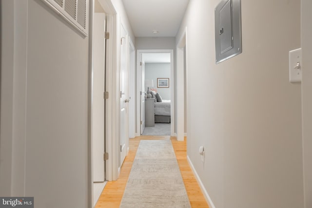 hallway featuring electric panel and light hardwood / wood-style flooring