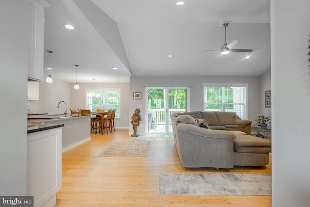 living room featuring light hardwood / wood-style flooring, vaulted ceiling, and ceiling fan