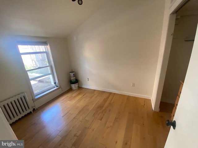 additional living space with radiator and light hardwood / wood-style flooring