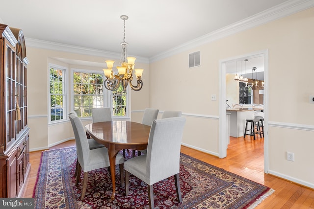 dining area featuring ornamental molding, a notable chandelier, and light hardwood / wood-style floors