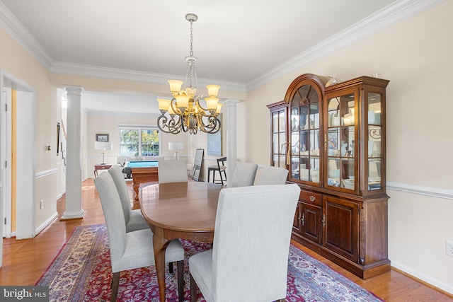 dining room featuring hardwood / wood-style flooring, crown molding, decorative columns, and a chandelier