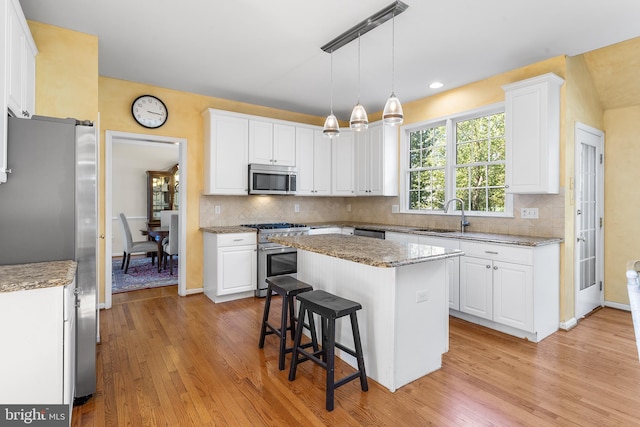 kitchen with light wood-type flooring, white cabinets, appliances with stainless steel finishes, and a center island