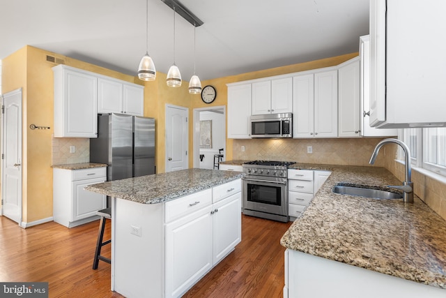 kitchen featuring white cabinets, appliances with stainless steel finishes, sink, and a center island