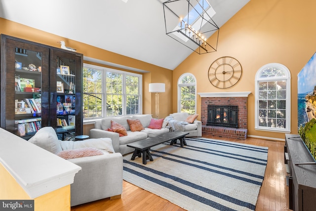 living room with high vaulted ceiling, a fireplace, and light hardwood / wood-style flooring