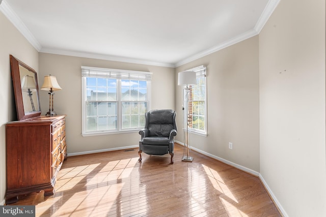 living area featuring a healthy amount of sunlight, crown molding, and light hardwood / wood-style floors