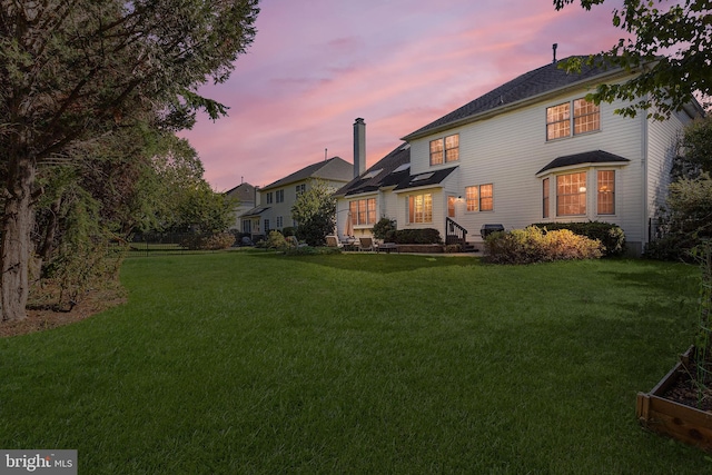 back house at dusk with a lawn