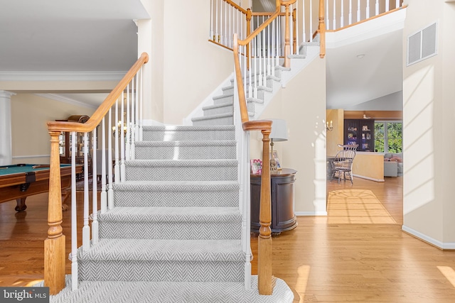 staircase with a high ceiling, hardwood / wood-style flooring, crown molding, and billiards