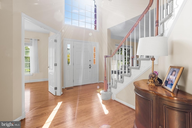 entryway with light wood-type flooring and a towering ceiling