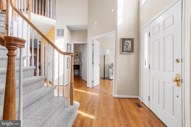 foyer entrance with light hardwood / wood-style floors and a high ceiling