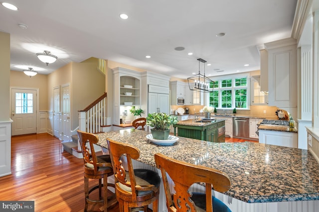 kitchen with light hardwood / wood-style flooring, built in appliances, a wealth of natural light, and a kitchen island