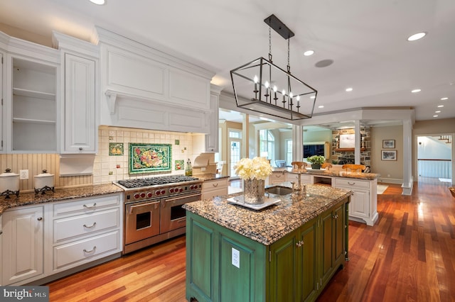 kitchen with white cabinets, green cabinetry, light hardwood / wood-style flooring, a center island, and range with two ovens