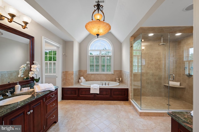 bathroom featuring lofted ceiling, tile walls, vanity, and independent shower and bath