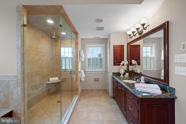 bathroom with vanity, a shower with shower door, tile patterned flooring, and a wealth of natural light