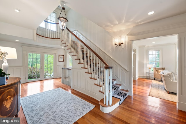 stairway with plenty of natural light, french doors, and wood-type flooring