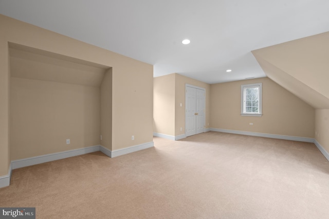 bonus room with vaulted ceiling and light carpet