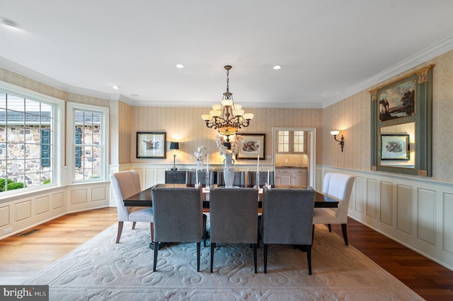 dining room featuring ornamental molding, light wood-type flooring, and an inviting chandelier