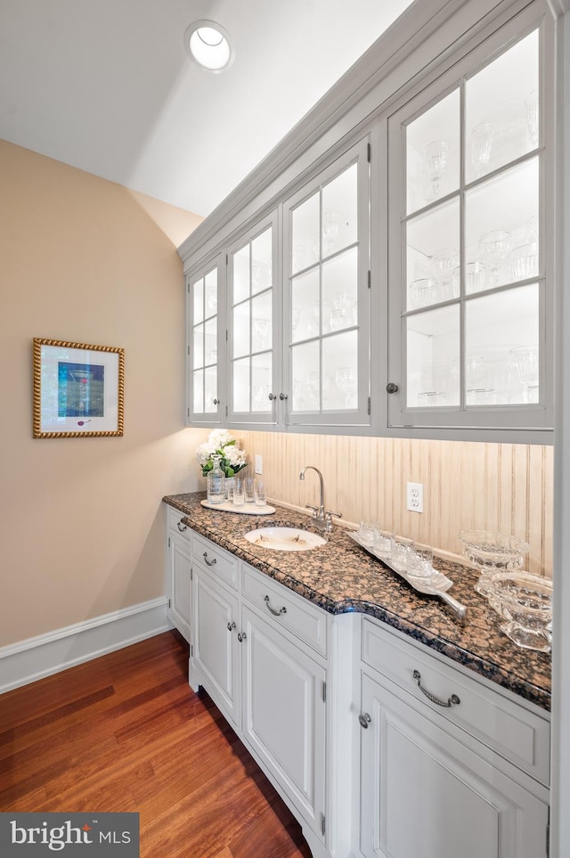 kitchen featuring dark stone countertops, white cabinets, sink, and dark hardwood / wood-style flooring