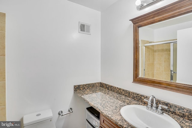 bathroom with an enclosed shower, vanity, and toilet