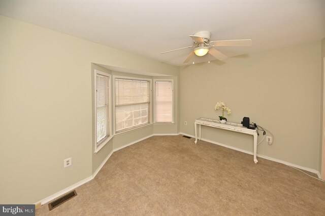 carpeted spare room with visible vents, ceiling fan, and baseboards