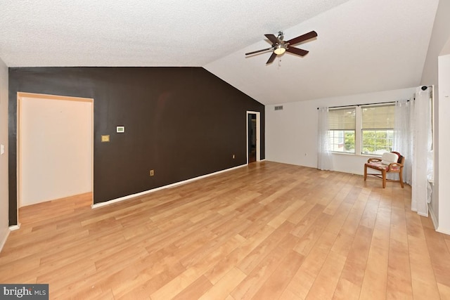 interior space featuring a textured ceiling, visible vents, a ceiling fan, vaulted ceiling, and light wood-style floors