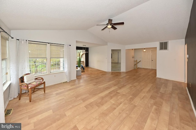 living room featuring light wood-type flooring, visible vents, and lofted ceiling