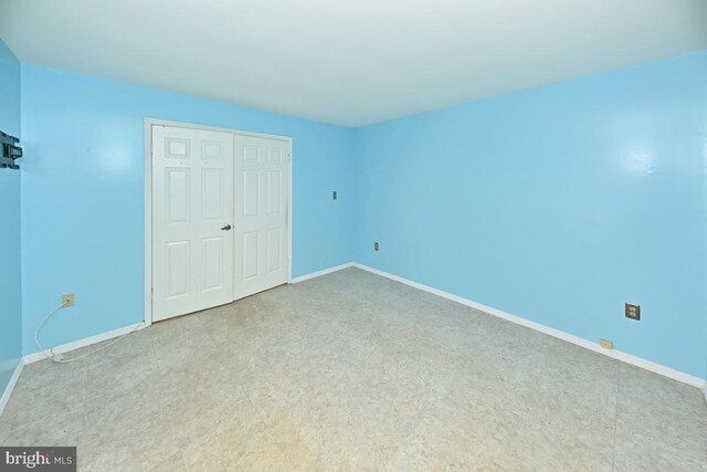 unfurnished bedroom with baseboards and a closet