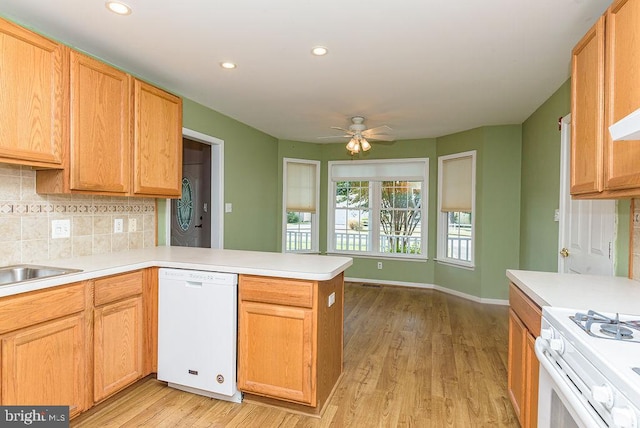 kitchen with ceiling fan, kitchen peninsula, white appliances, light hardwood / wood-style flooring, and backsplash