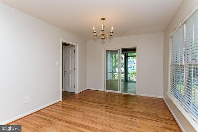 unfurnished room featuring light wood-type flooring and a chandelier