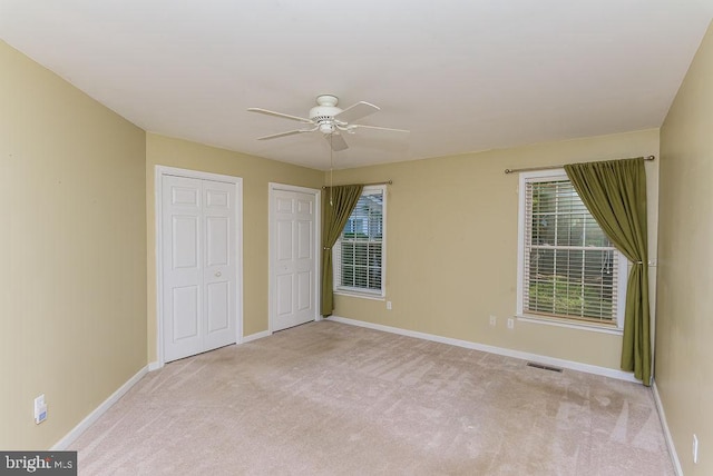 unfurnished bedroom featuring multiple windows, ceiling fan, and light colored carpet