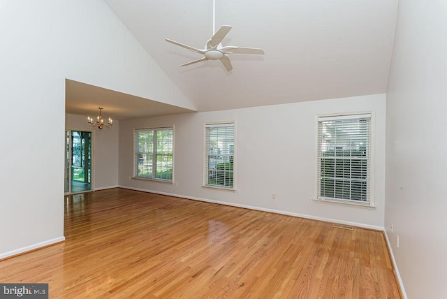 spare room with ceiling fan with notable chandelier, light hardwood / wood-style floors, and high vaulted ceiling