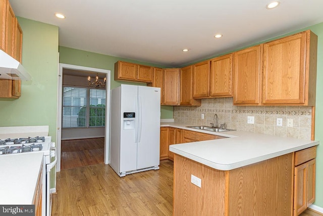 kitchen with sink, white appliances, tasteful backsplash, a chandelier, and light hardwood / wood-style floors