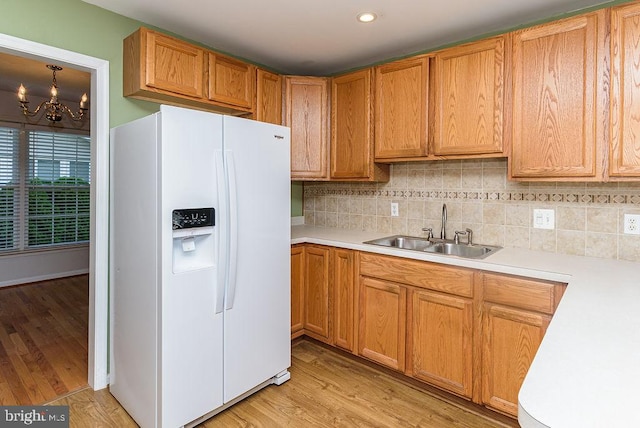 kitchen featuring an inviting chandelier, light hardwood / wood-style floors, white refrigerator with ice dispenser, and sink