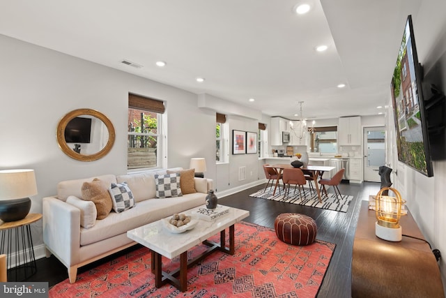 living room with a notable chandelier and dark wood-type flooring