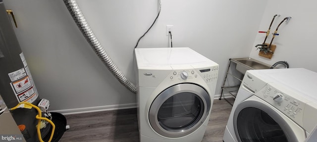 washroom featuring water heater, separate washer and dryer, and dark hardwood / wood-style flooring