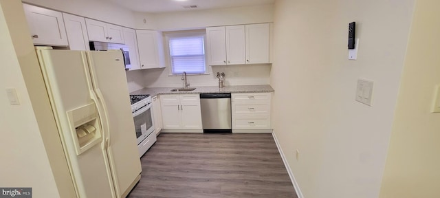 kitchen with white cabinets, hardwood / wood-style floors, sink, and white appliances