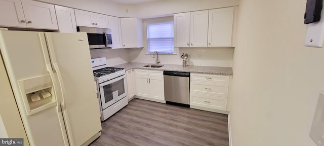 kitchen featuring light hardwood / wood-style flooring, white cabinetry, appliances with stainless steel finishes, light stone countertops, and decorative backsplash