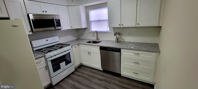 kitchen featuring white cabinets, dark stone countertops, dark wood-type flooring, sink, and appliances with stainless steel finishes