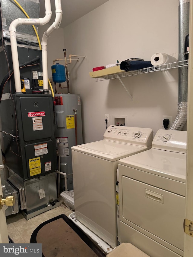 washroom with washing machine and clothes dryer, heating unit, and electric water heater