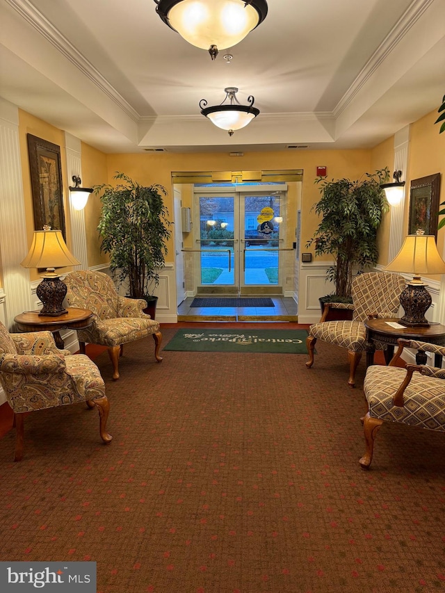 sitting room featuring carpet flooring, a tray ceiling, and ornamental molding