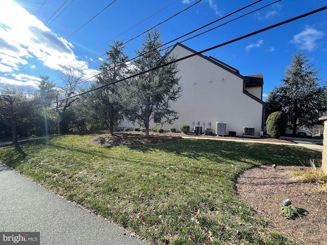 view of property exterior with a yard and central air condition unit