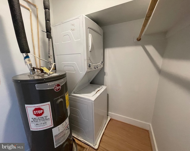 laundry area with hardwood / wood-style flooring, stacked washer / drying machine, and water heater