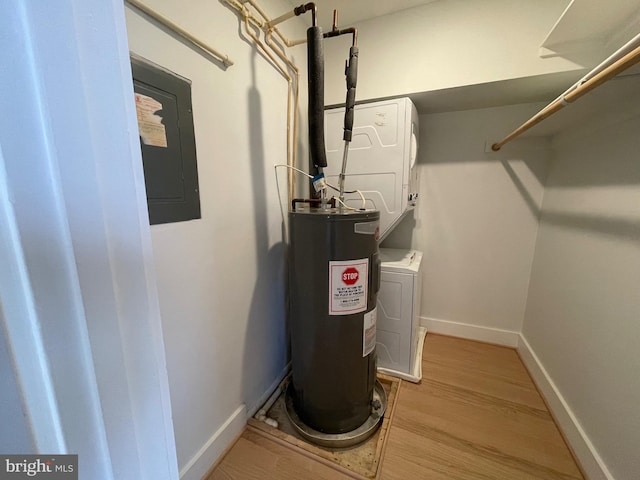 utilities with electric panel, electric water heater, and stacked washer / drying machine