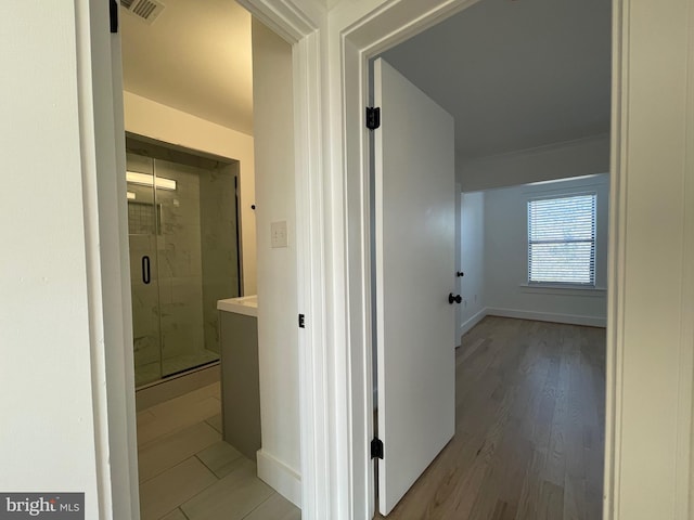 corridor with light hardwood / wood-style floors and crown molding