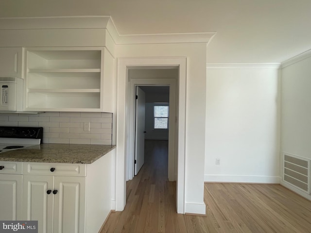 interior space with white cabinets, dark stone countertops, white appliances, and light hardwood / wood-style flooring