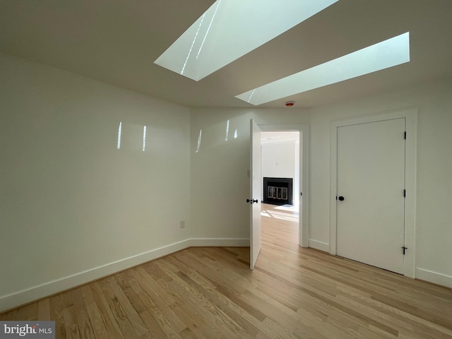 empty room with a skylight and light wood-type flooring