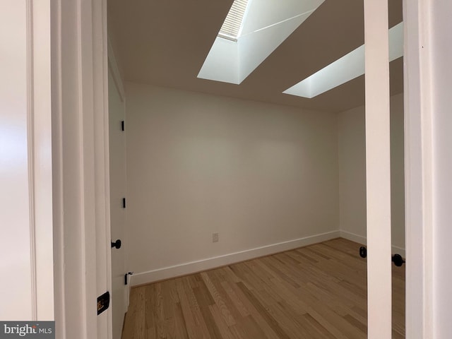 additional living space with a skylight and light hardwood / wood-style flooring