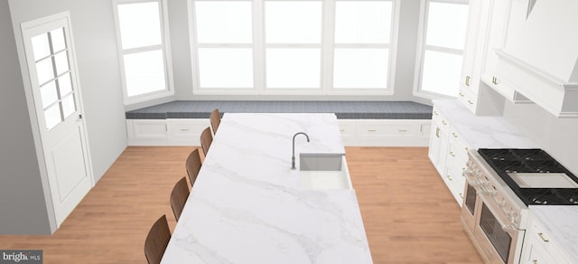 kitchen featuring light hardwood / wood-style floors, sink, stainless steel stove, white cabinetry, and light stone countertops