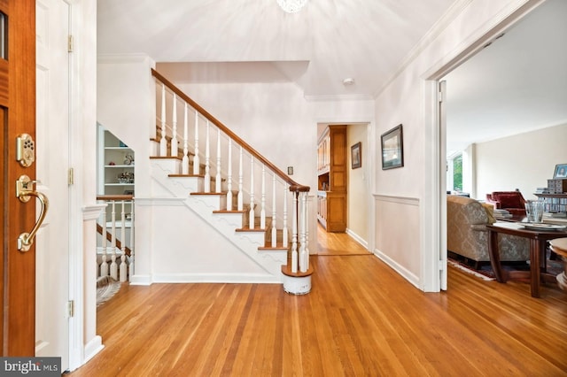 entrance foyer with crown molding and light hardwood / wood-style floors