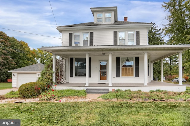 farmhouse-style home featuring a front yard, covered porch, a garage, and an outbuilding